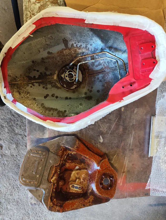 Réservoir ouvert, intérieur corrodé, posé sur l'établi