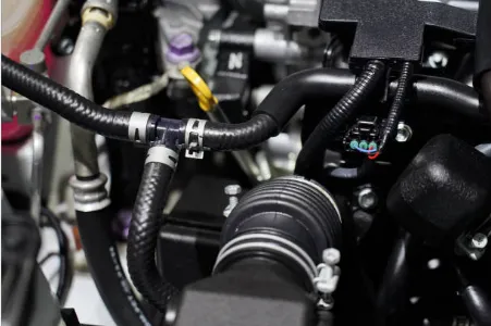 Durites caoutchouc noires et colliers de serrage dans un compartiment moteur