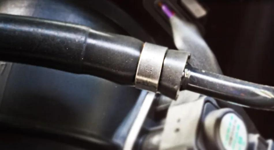 Durite en caoutchouc noire raccordée par un collier dans un compartiment moteur