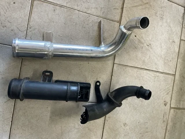 Tube aluminium d’origine et durites caoutchouc coudées déposés côte à côte
